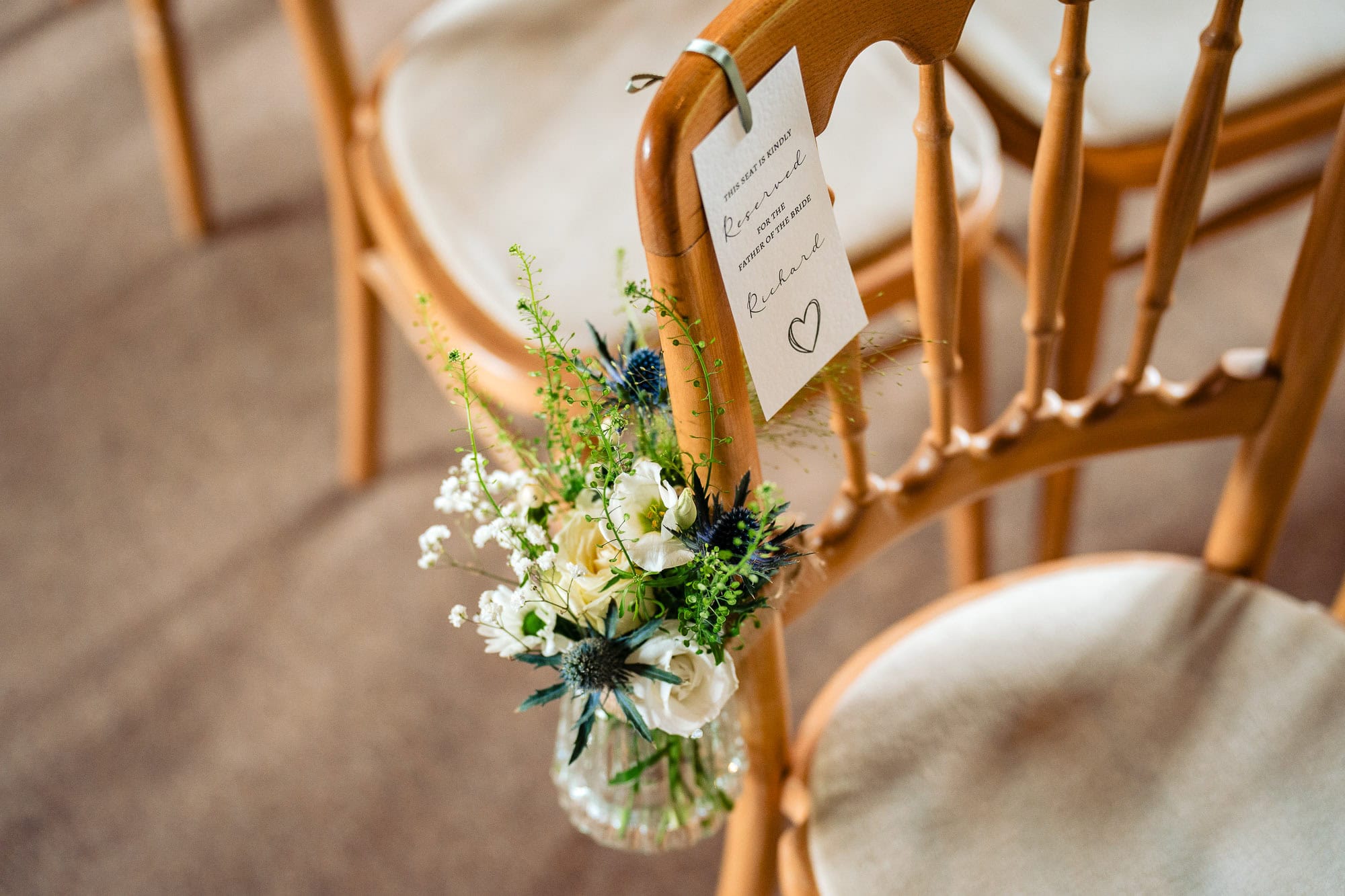 Clock Barn wedding, white flowers in glass vases on the chairs in the aisle. 