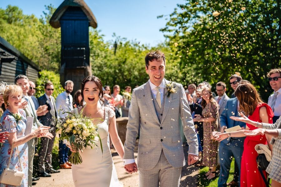 Clock Barn wedding venue in Hampshire, confetti throw of the couple and guests with the clock tower in the background