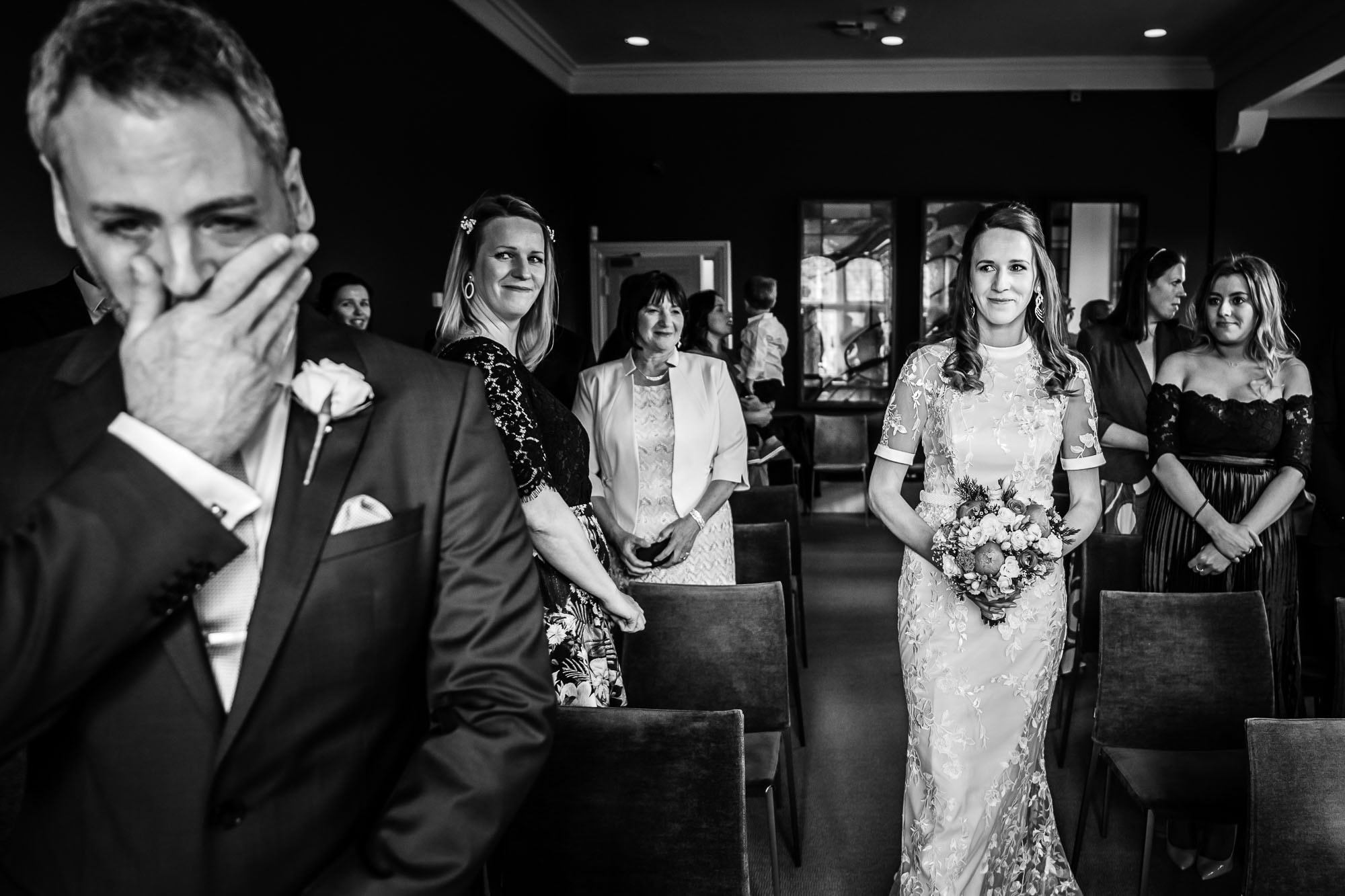 Bride walking down the aisle, groom emotional, black and white wedding photo at Winchester Registry Office